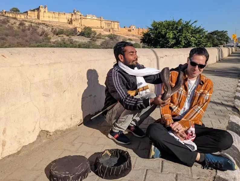 A snake charmer puts his cobra on Adams shoulder